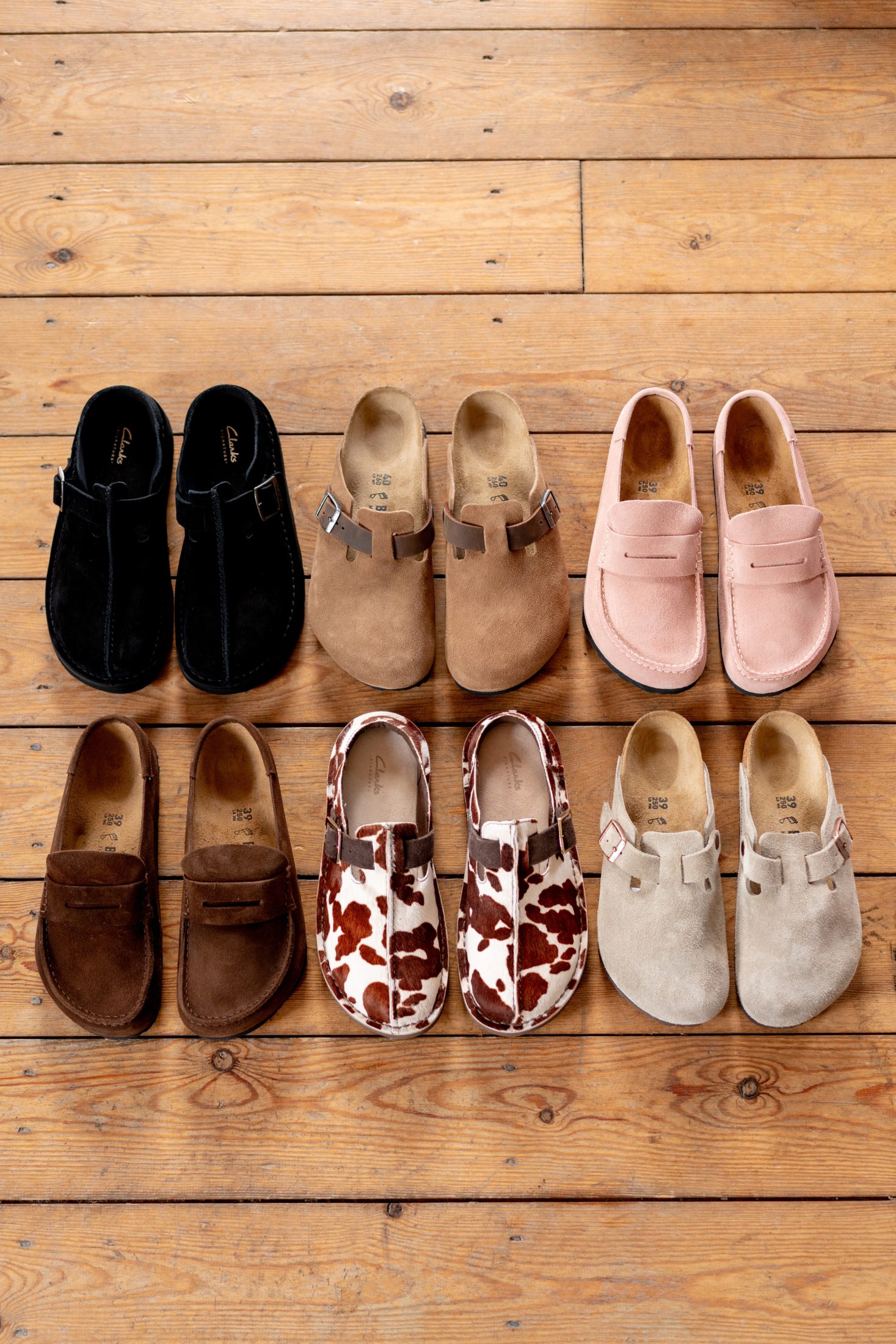 Clarks Original Solsbury Mule, Birkenstock Boston and Birkenstock Boston in different colourways on a wooden floor